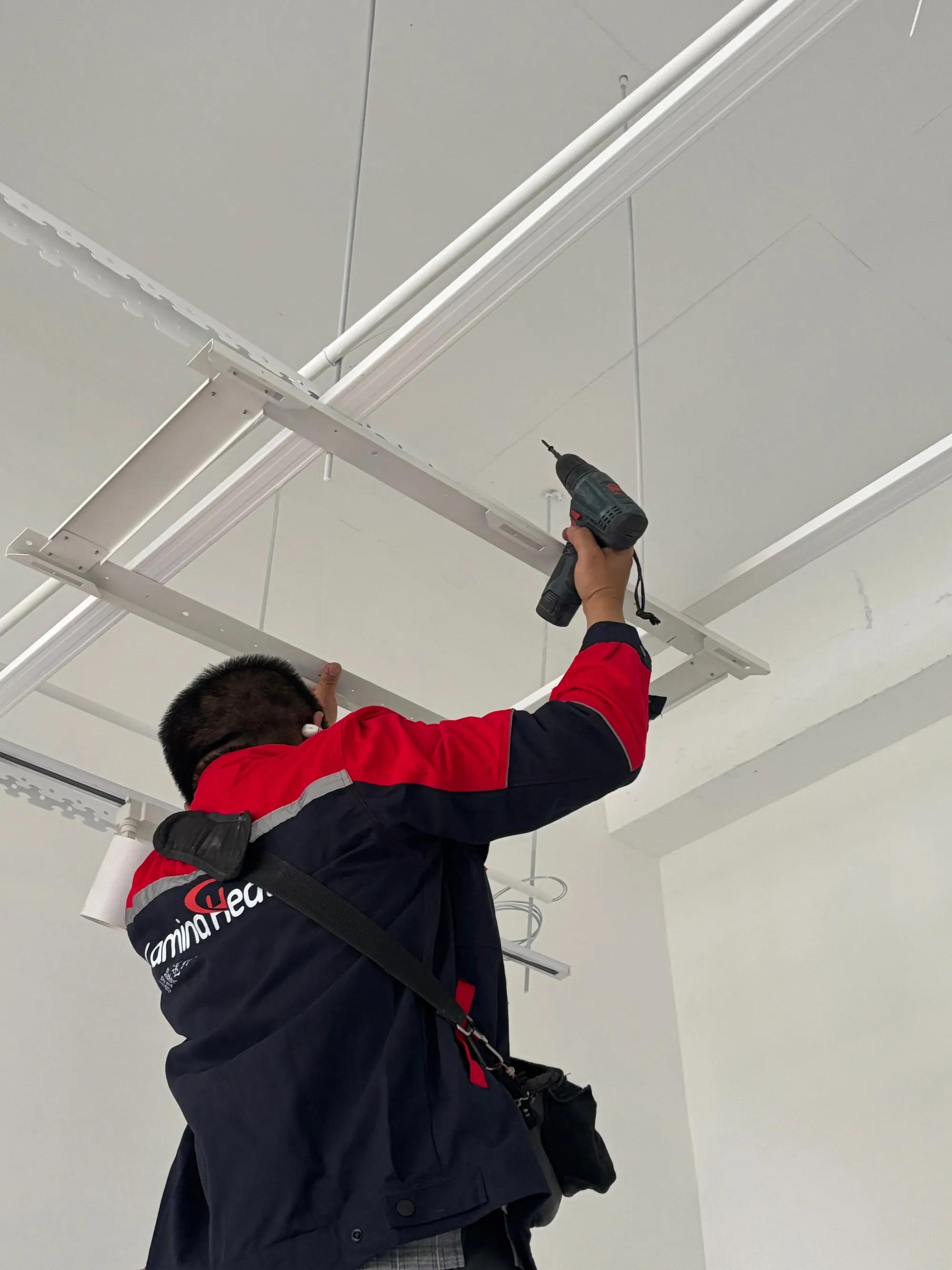 An installer fixing the mounting frame for a PowerBoard panel to a finished ceiling