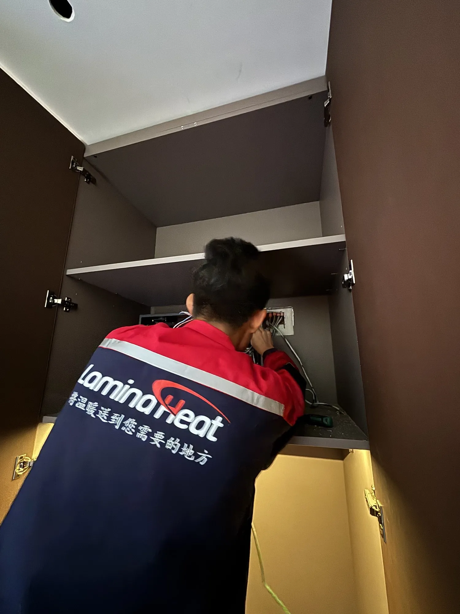 A LaminaHeat installer connecting the power supply inside a built-in cupboard
