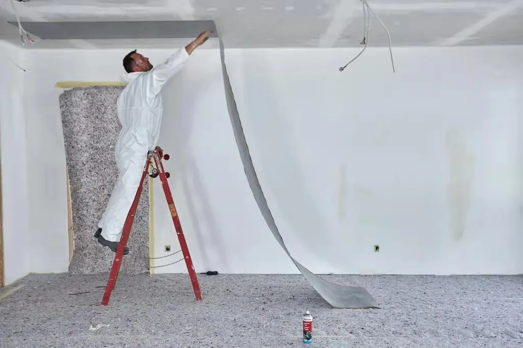 An installer unrolling a length of ComfortScrim down a wall